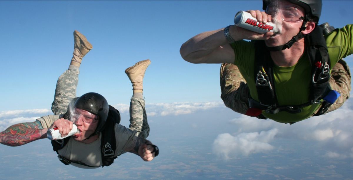 Two skydivers drinking Kill Cliff energy drinks mid-air, showcasing the brand's adventurous and bold spirit.