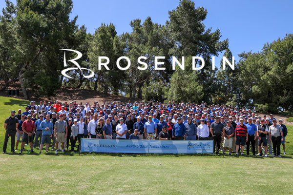 A large group of people are gathered outdoors with a banner for the Rosendin Annual Golf Tournament.