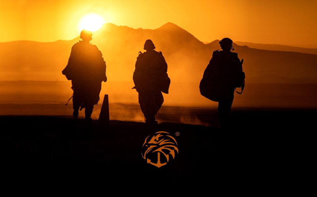 Silhouettes of soldiers walking against a sunset backdrop, with a logo resembling a stylized eagle head. Navy seal wallpaper might apply.