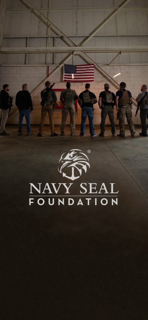 People stand beneath an American flag in a hangar with "Navy Seal Foundation" branding. Navy seal wallpaper applies.