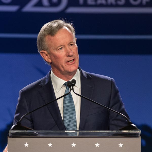 Admiral William McRaven, dressed in a suit and tie, speaks at a podium during an event, with a blue backdrop for the Courage & Civility Award.